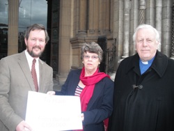 Mr Adrian Horsman of Christian Aid Ireland receives a cheque for £100,000 from Mrs Roberta McKelvey. Looking on his the Dean of Belfast, the Very Rev Dr Houston McKelvey.
